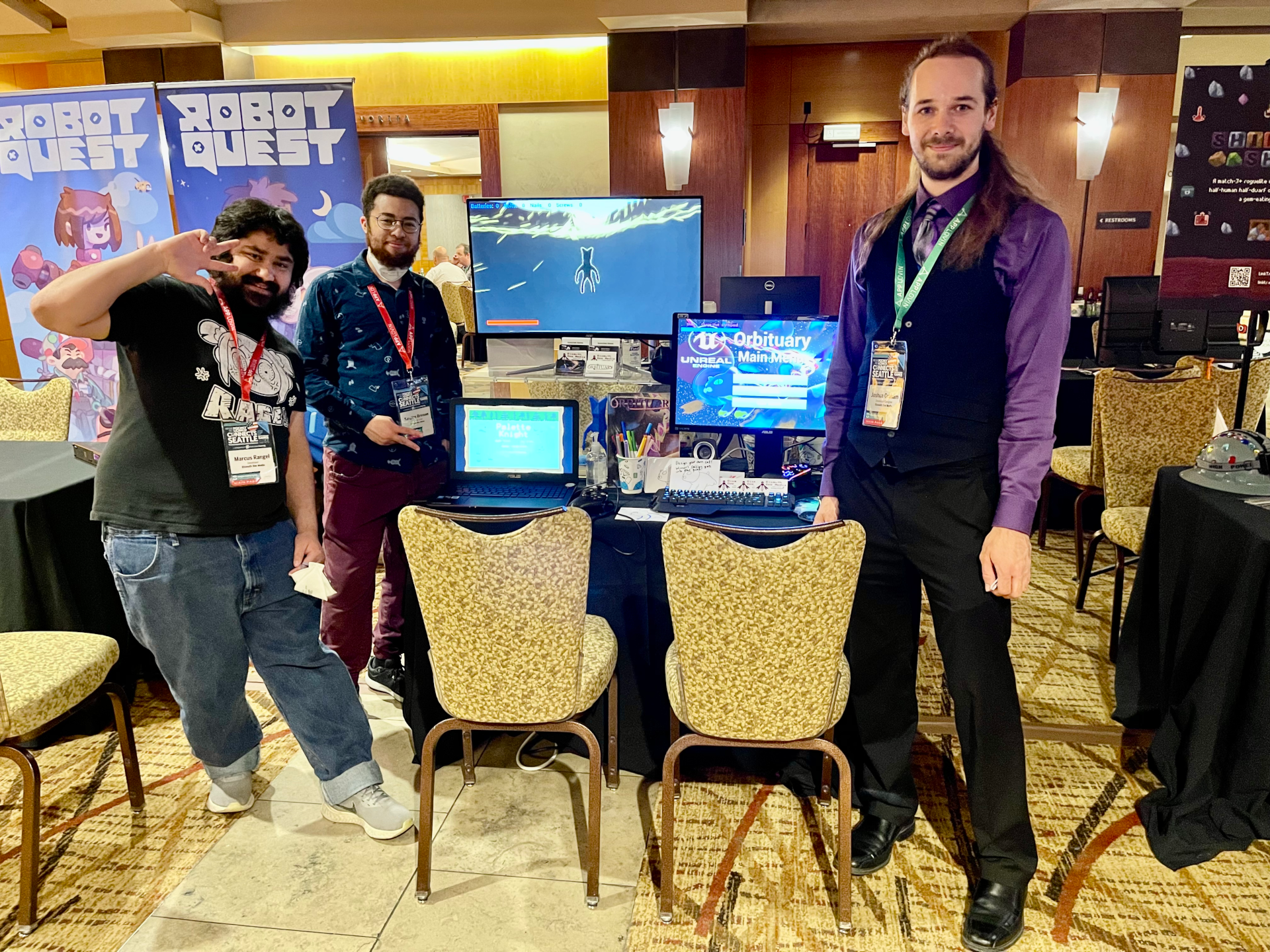 Salem, Kaspian, and Joshua standing at their table, showcasing Orbituary and other Bismuth Bee Games